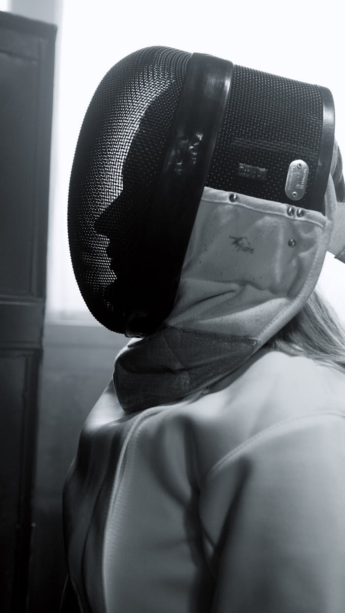 Close-up of a fencer in traditional gear, captured in black and white.