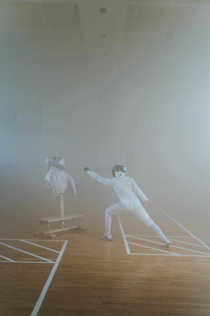 A fencer practicing with a dummy in a smoke-filled room, showcasing stance and athleticism.
